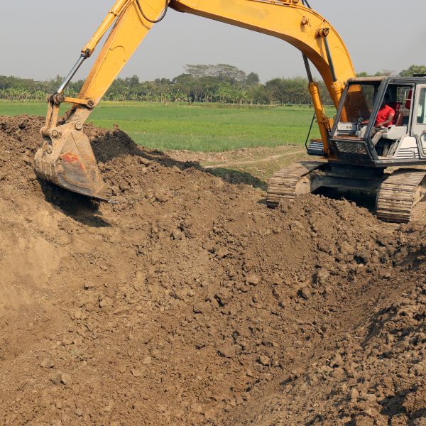 Excavator digging earth for rural dam construction in a farm paddock, by Rural Property Services NSW. Excavator digging earth for rural dam construction in a farm paddock, by Rural Property Services NSW.