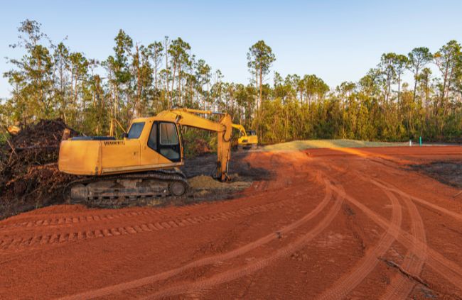 Excavator on graded rural site with compacted red earth, part of expert land grading and levelling by Rural Property Services NSW.
