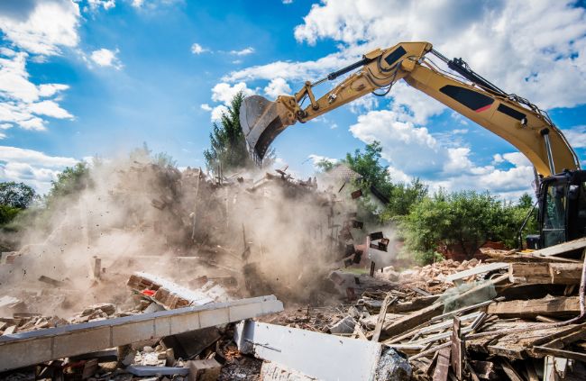 Excavator tearing down a rural structure, sending up dust as debris falls during a demolition job by Rural Property Services NSW. Excavator tearing down a rural structure, sending up dust as debris falls during a demolition job by Rural Property Services NSW.