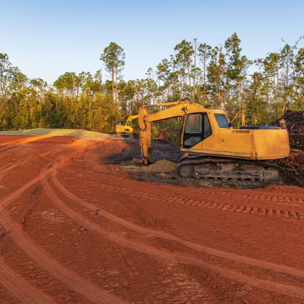 Excavator working on freshly levelled soil site, part of rural site preparation and pad levelling by Rural Property Services NSW.