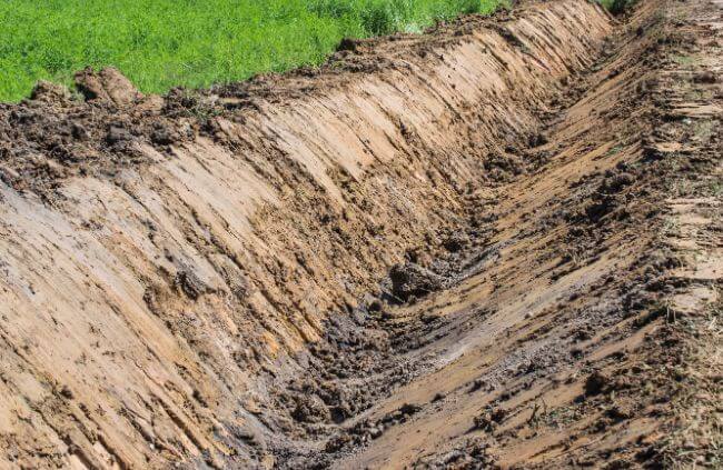 Freshly dug open earth drain shaped for rural property drainage to manage stormwater runoff by Rural Property Services NSW. Freshly dug open earth drain shaped for rural property drainage to manage stormwater runoff by Rural Property Services NSW.