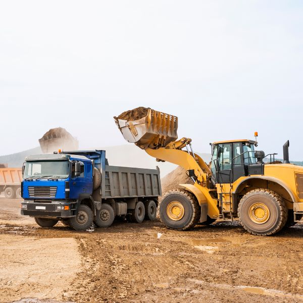 Front loader loading soil into a tipper truck for rural haulage services by Rural Property Services NSW.