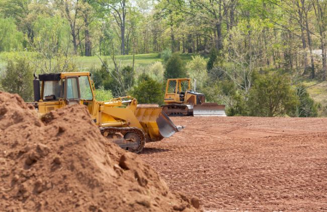 Heavy machinery clearing land and shaping a rural site for building at Rural Property Services NSW, showing land clearing, grading and levelling, and site prep work.