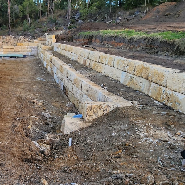 Sandstone block wall installation showing site cut and stepped construction by Rural Property Services NSW Sandstone block wall installation showing site cut and stepped construction by Rural Property Services NSW