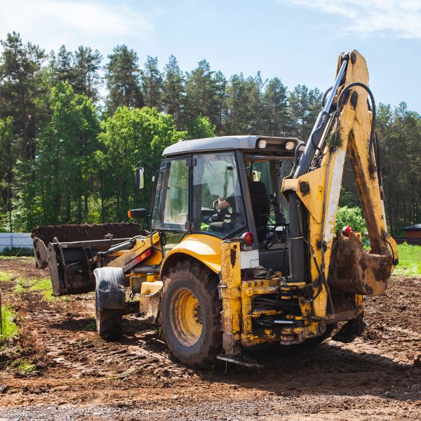 Backhoe loader performing land clearing on a rural property, preparing the site for future use by Rural Property Services NSW