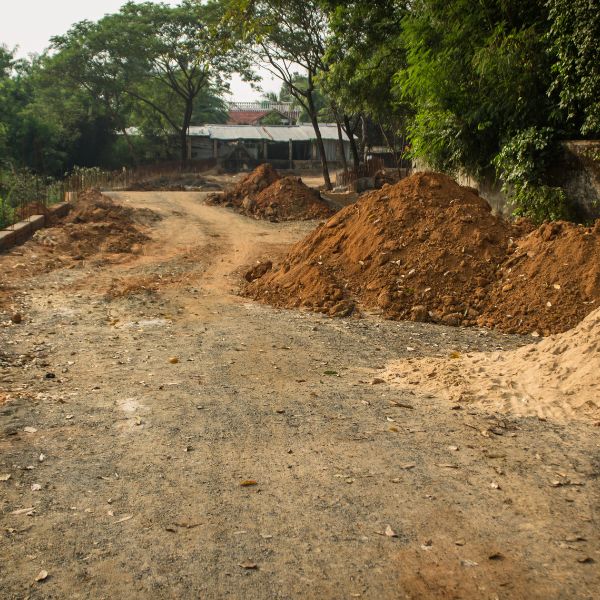 Dirt mounds beside a bush track during rural driveway construction by Rural Property Services NSW, with the site prepped for grading and compaction