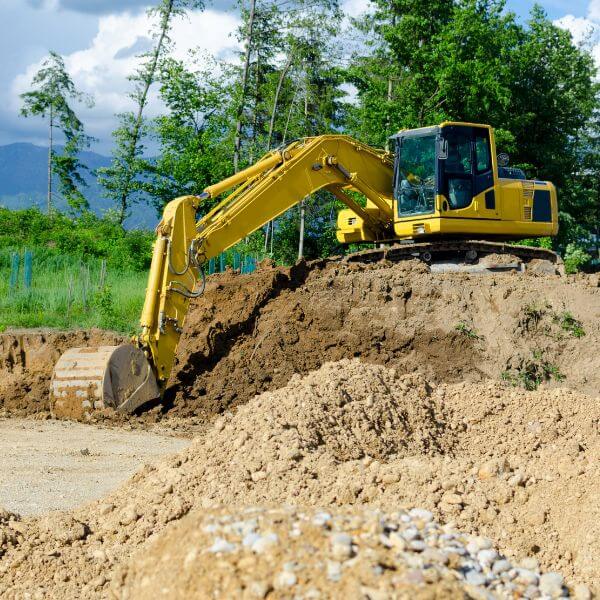 Excavator digging into rugged land during earthmoving services in Kenthurst by Rural Property Services NSW, working on a dam cleanout and pad levelling.