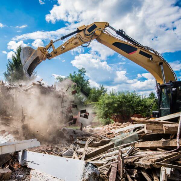 Excavator tearing down a rural structure during demolition and rubbish removal by Rural Property Services NSW